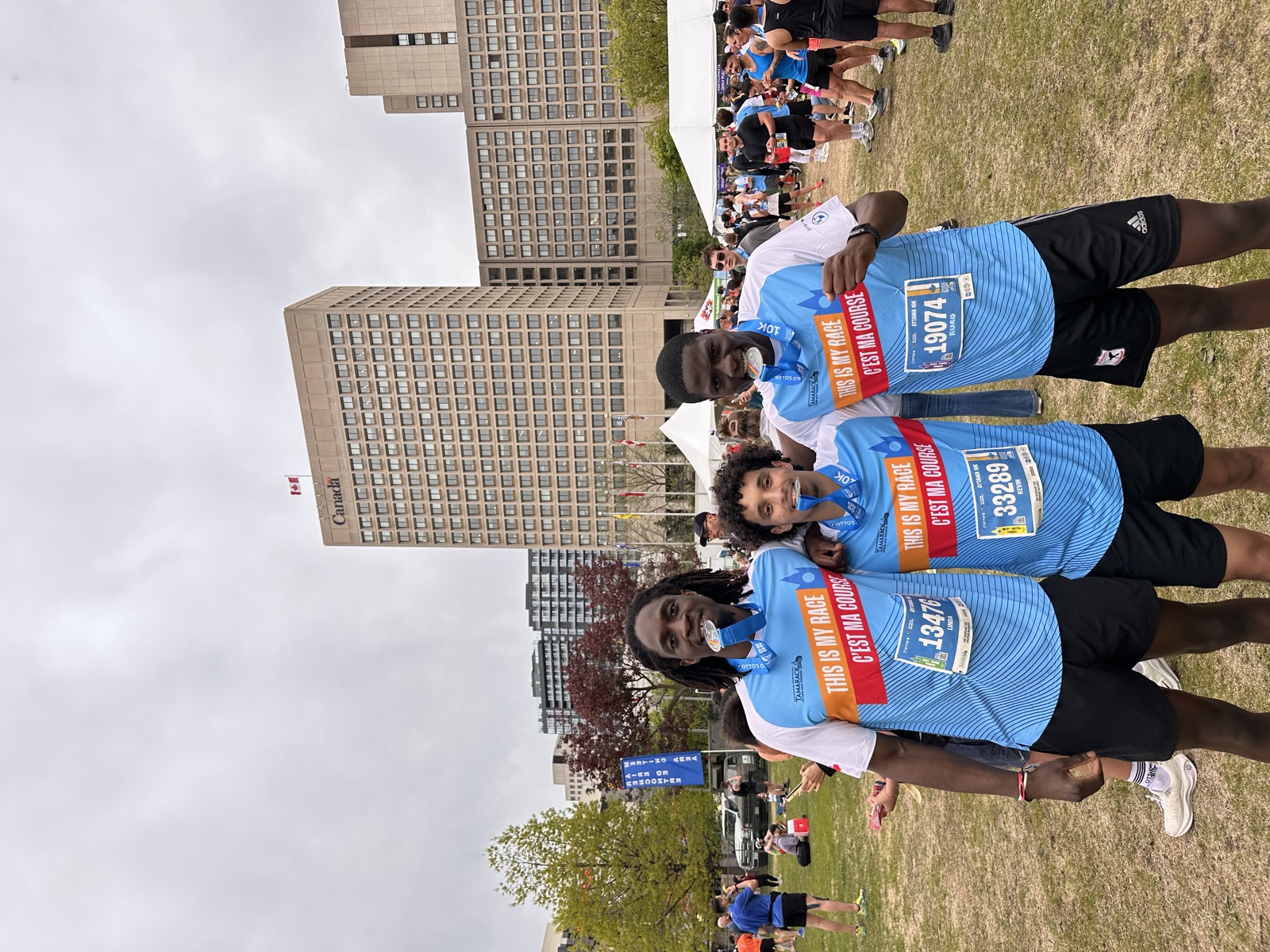 The founder and two friends after a 10K, medals in their teeth